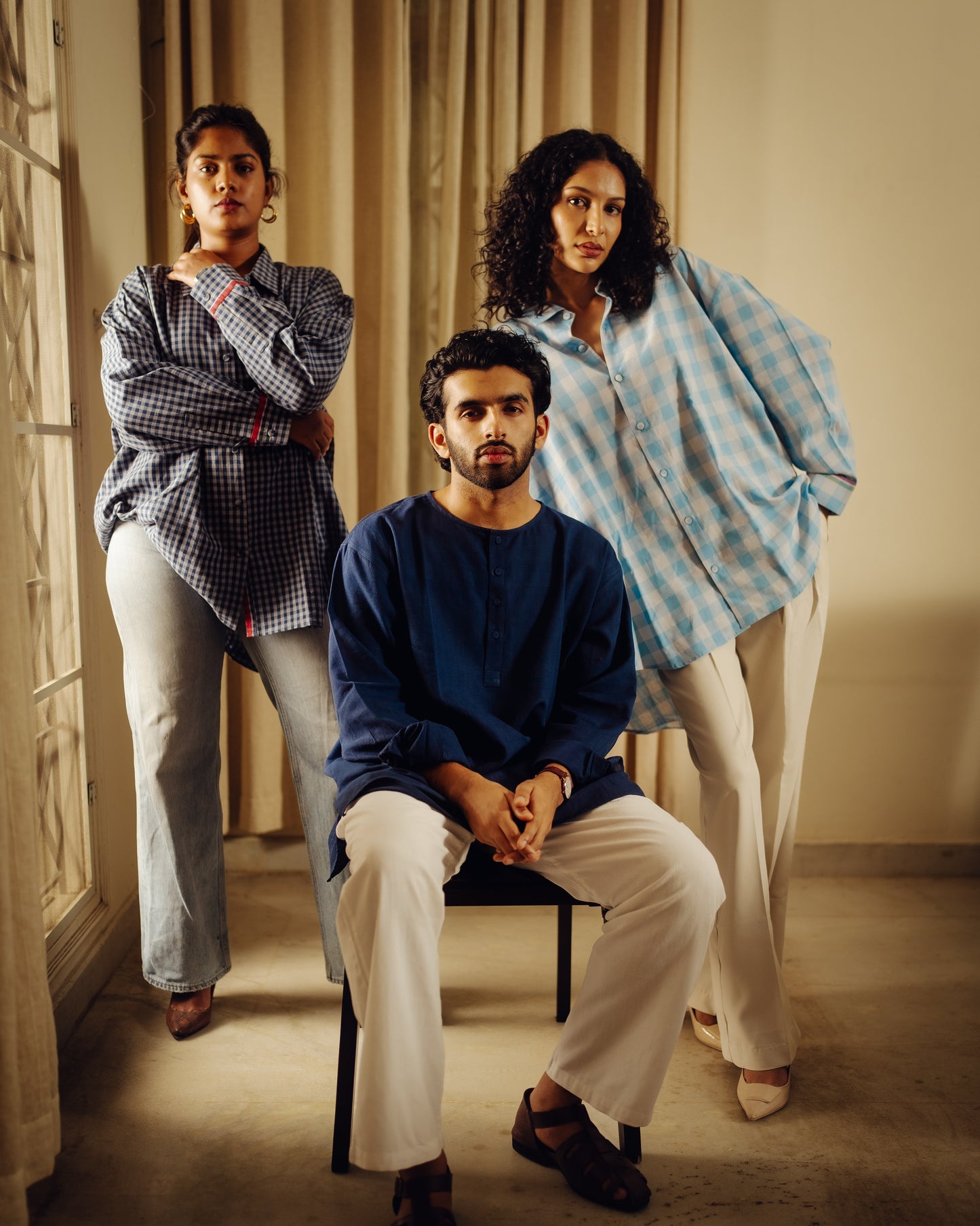 Three people wearing treeandpoetry dresses posing indoors with a neutral background
