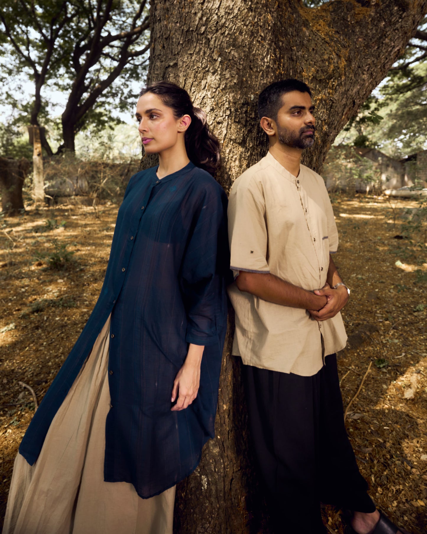 Two people standing under a tree in a natural setting