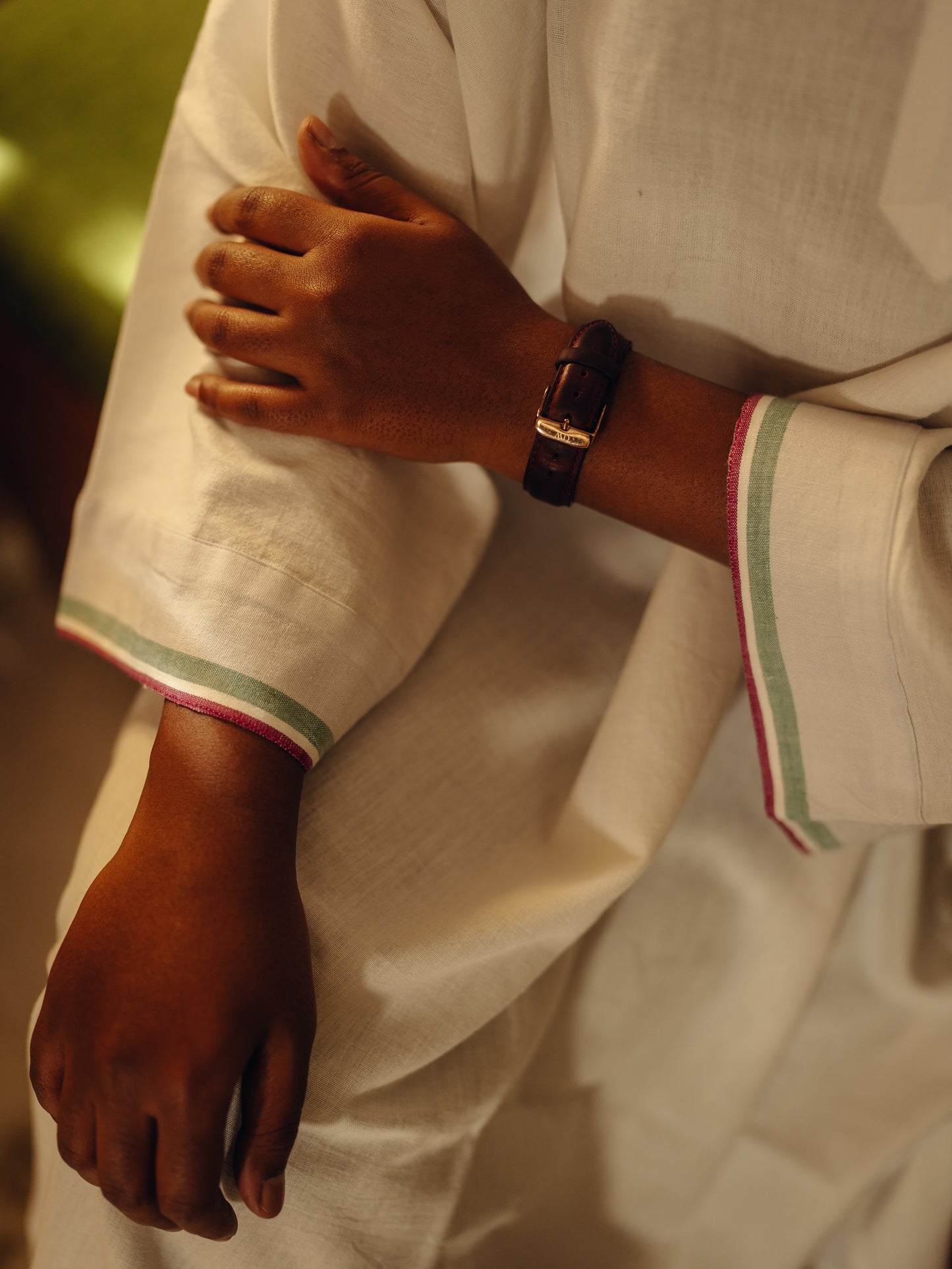Close-up of a person wearing a Oversized kurta - White with green trim, holding their arm.