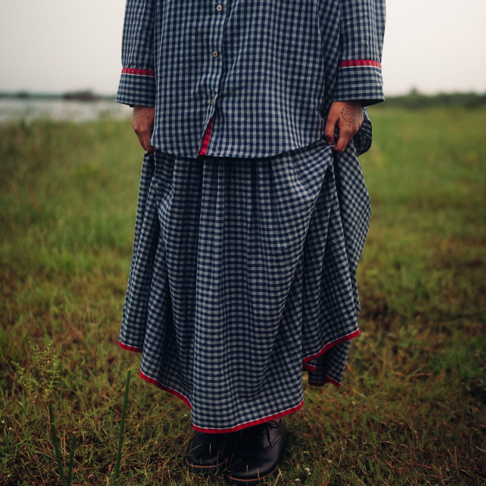 Person wearing a checkered outfit standing in a field