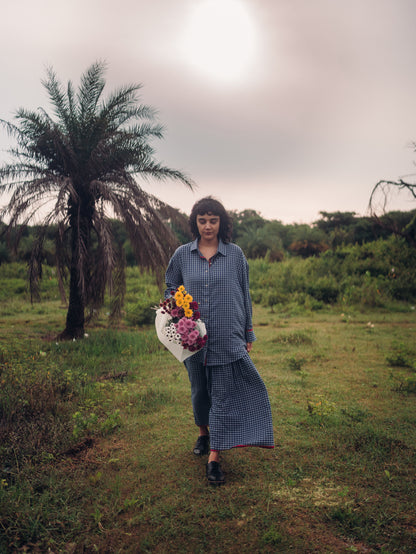 Person holding flowers in a grassy field with a palm tree