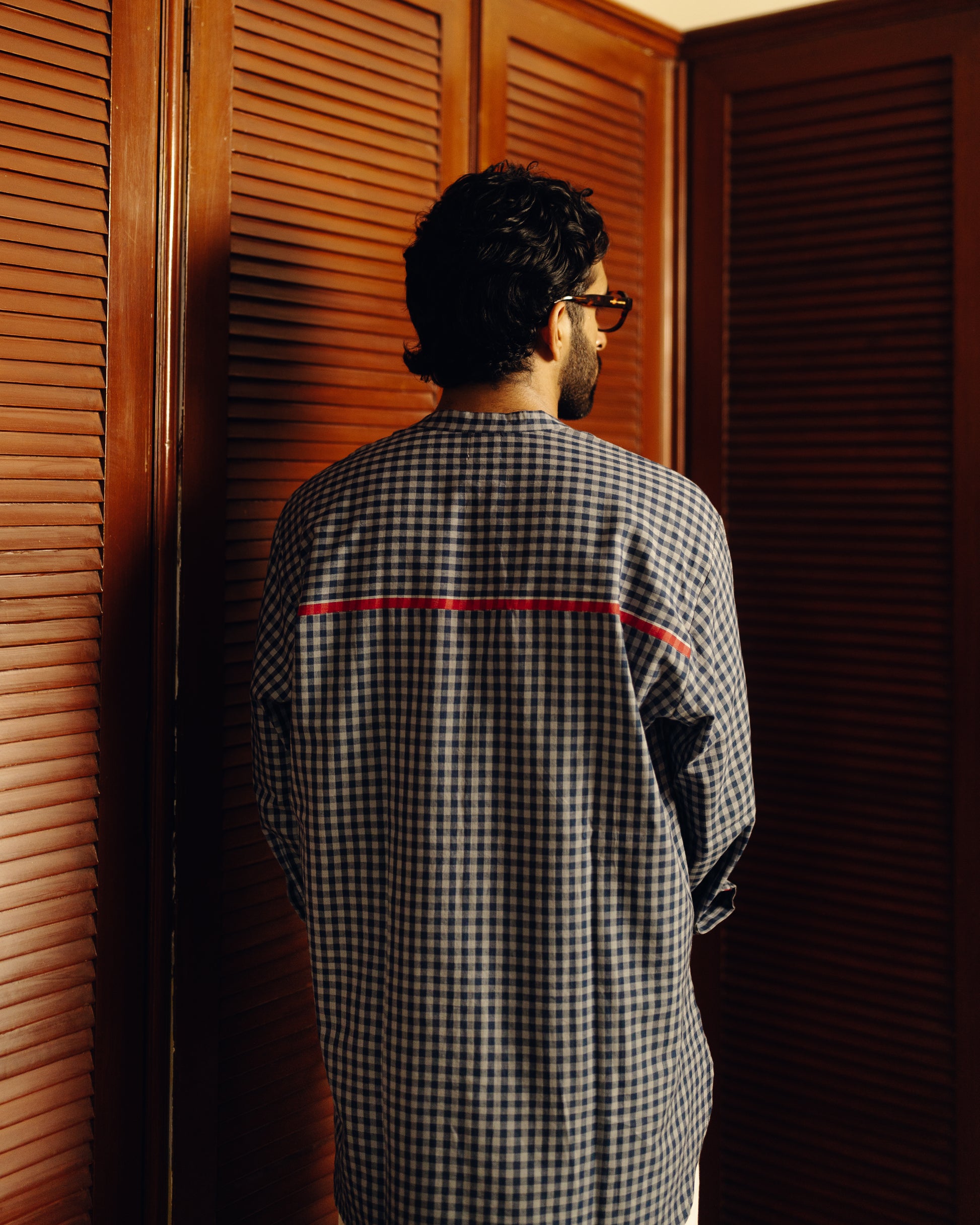 Man wearing a Blueberry checks - full sleeve shirt standing in front of wooden shutters.