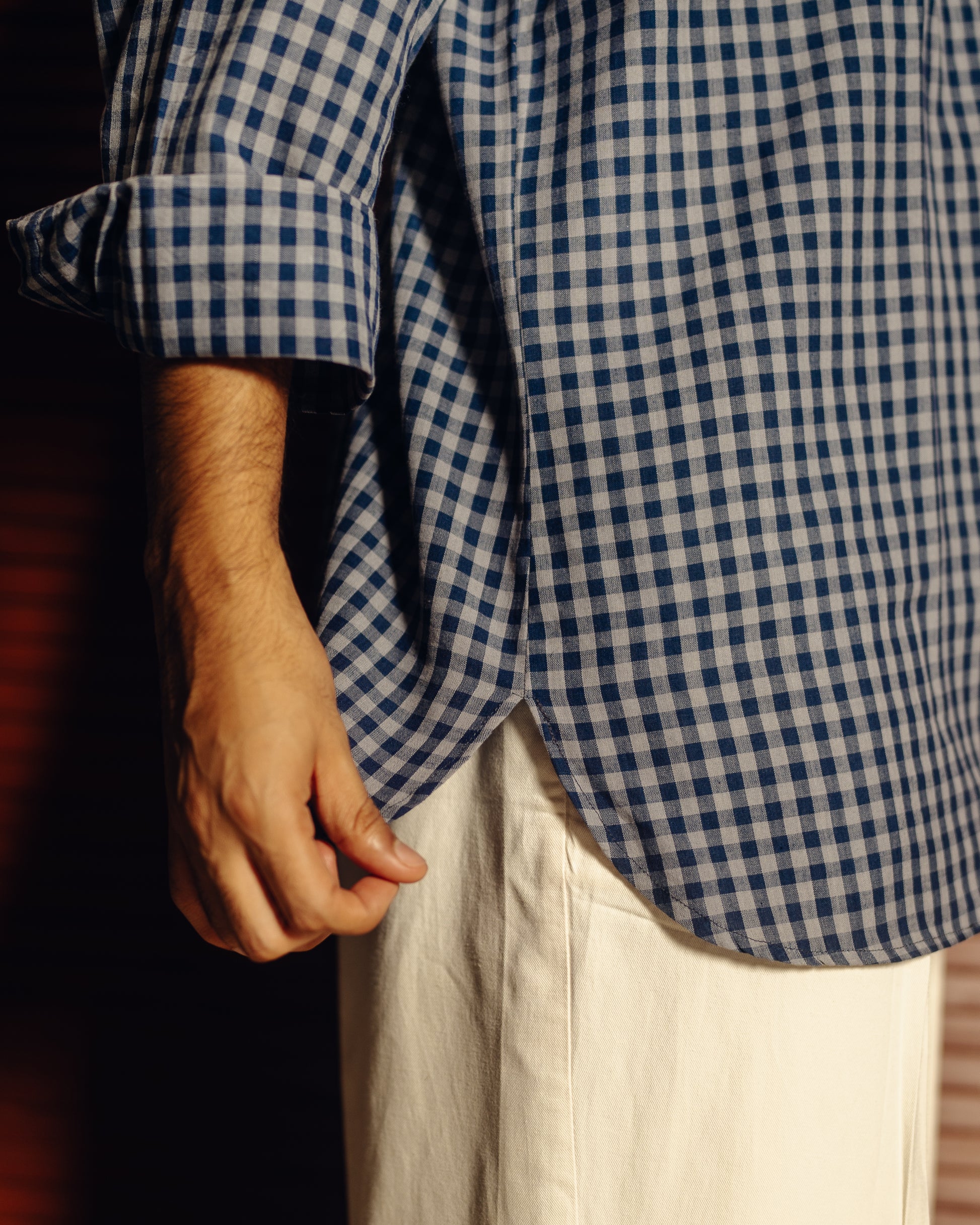 Person wearing a Blueberry checks - full sleeve shirt and white pants standing in a room with curtains and a sofa.