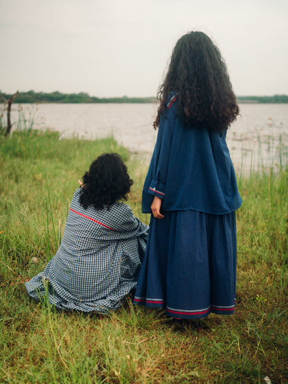 Two women in traditional clothing sitting by a lake.