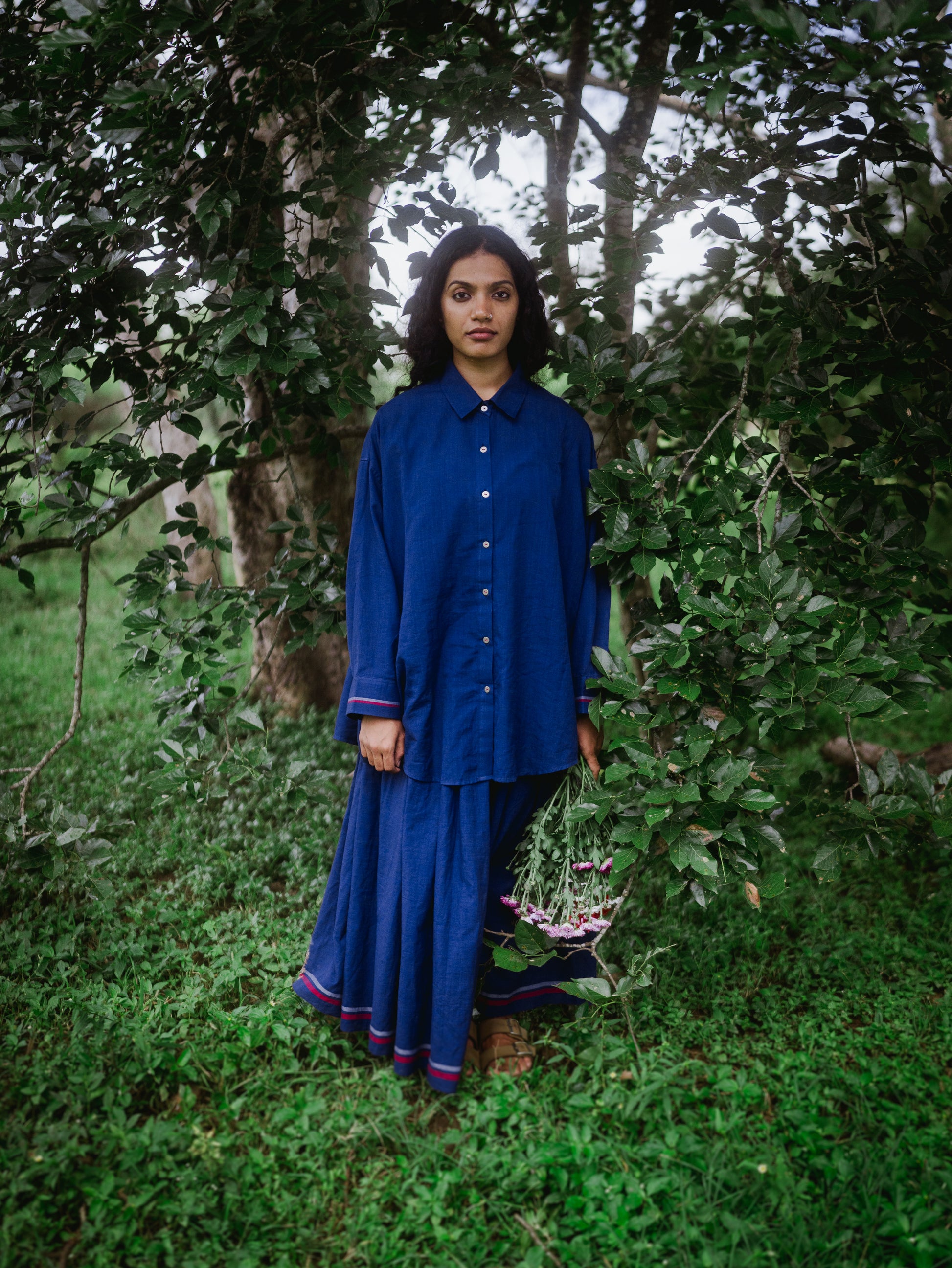 Woman in a blue outfit standing in a forest setting