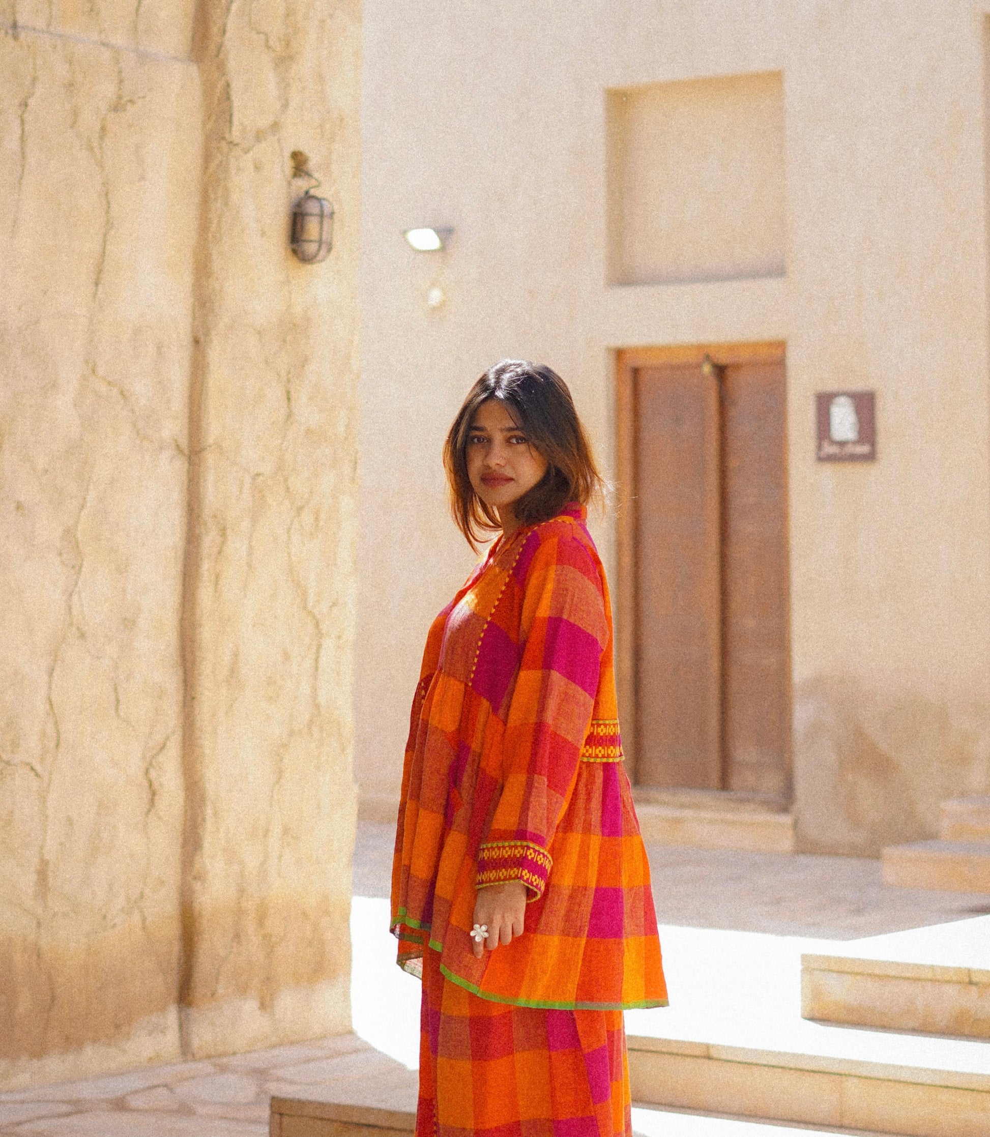 Woman in a colorful dress standing in front of a stone building.