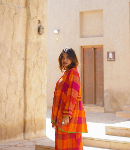 Woman in a colorful dress standing in front of a stone building.
