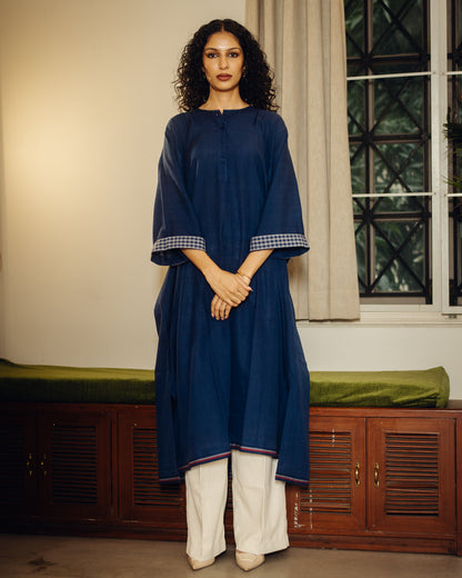 Woman wearing a blue kurta with white pants standing indoors.