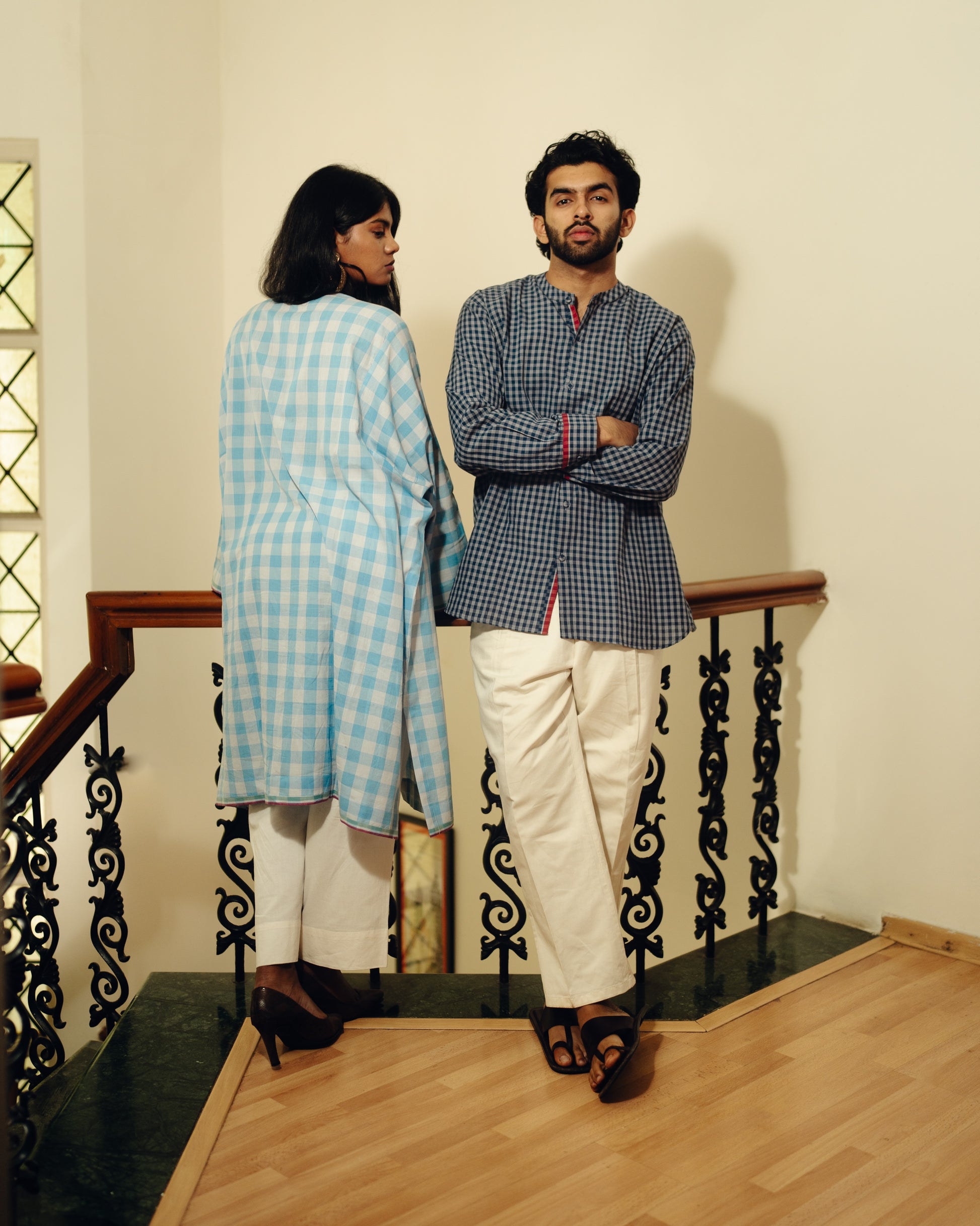 Two people standing on a staircase wearing matching checkered outfits.