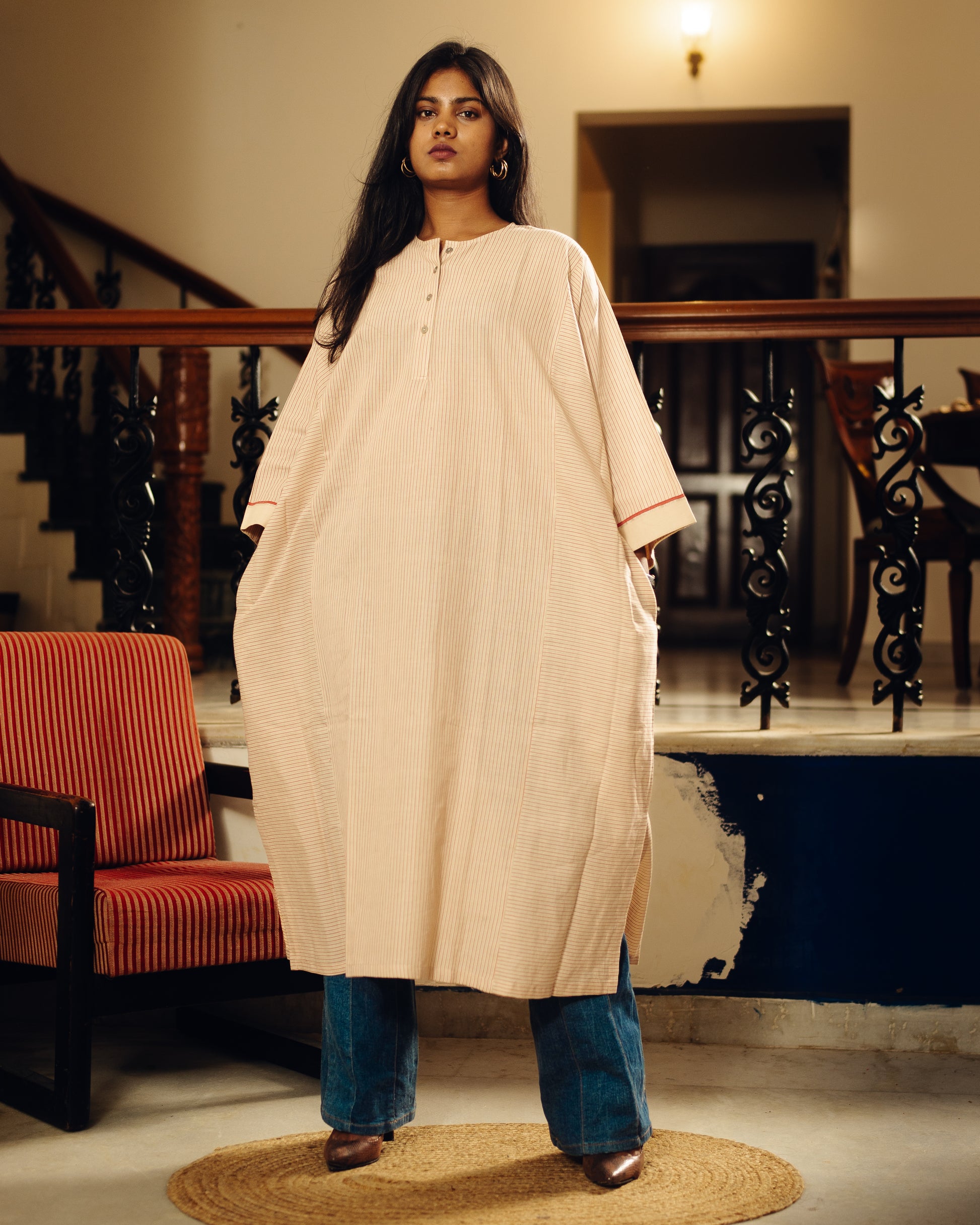 Woman wearing a Free size kurta - sand stripes with blue jeans in an indoor setting.