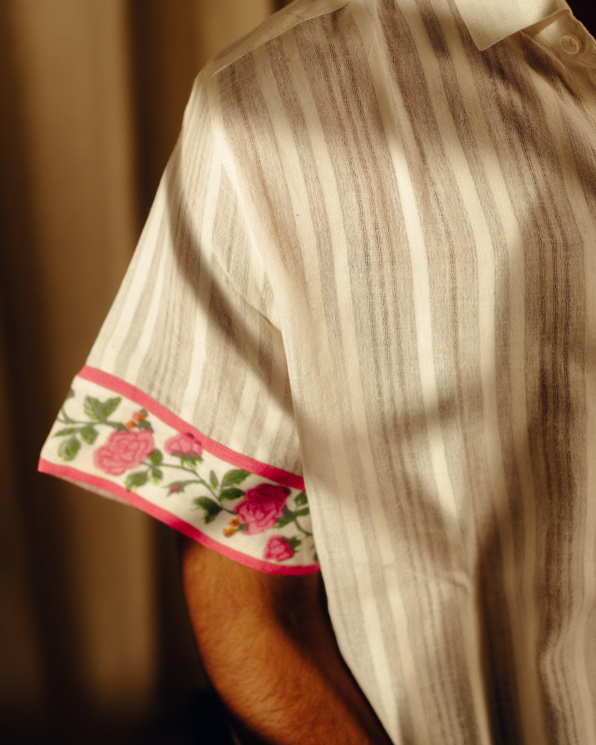 Close-up of a shirt with floral cuffs and hem against a blurred background