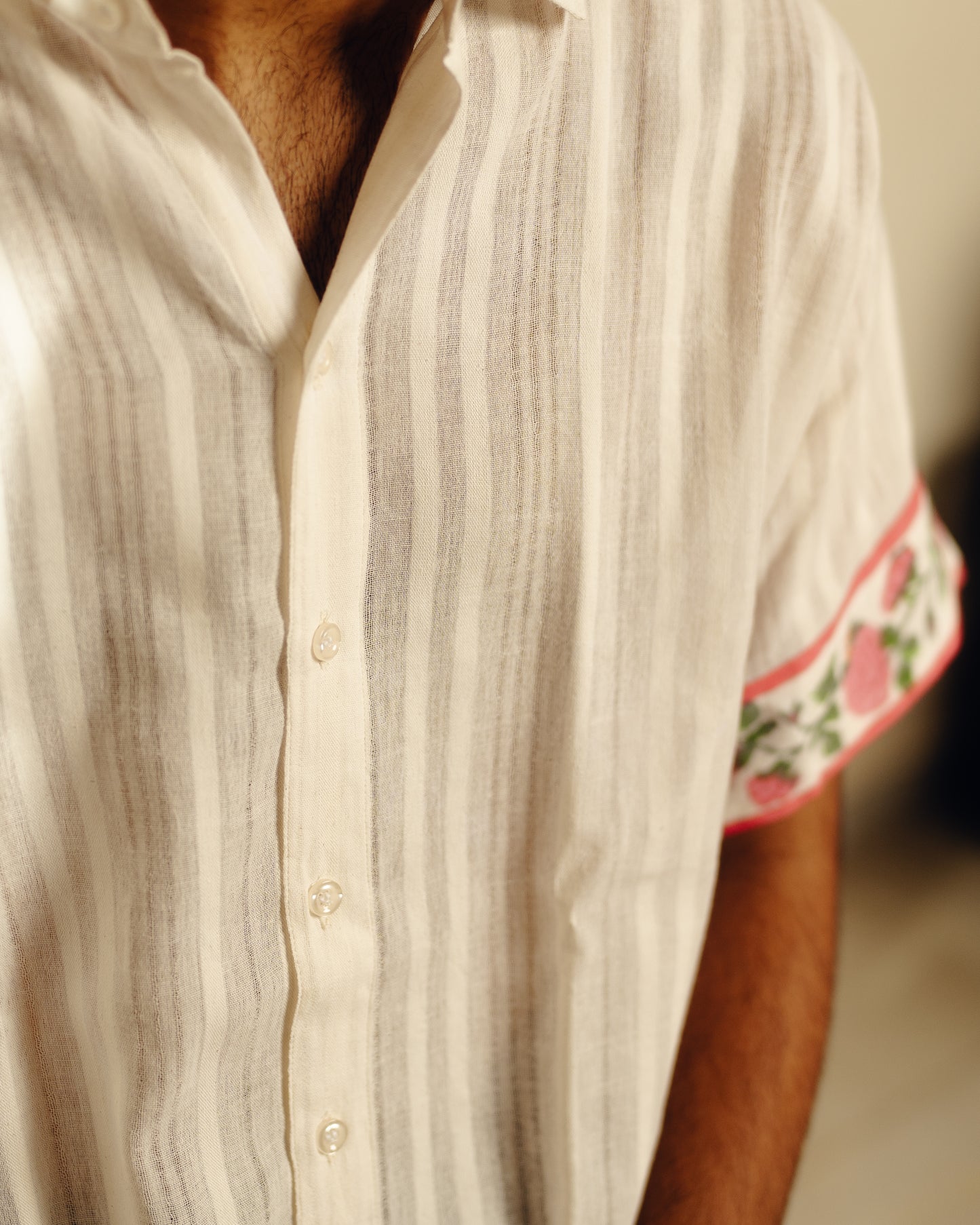 Close-up of a person wearing a white striped shirt with floral cuffs.