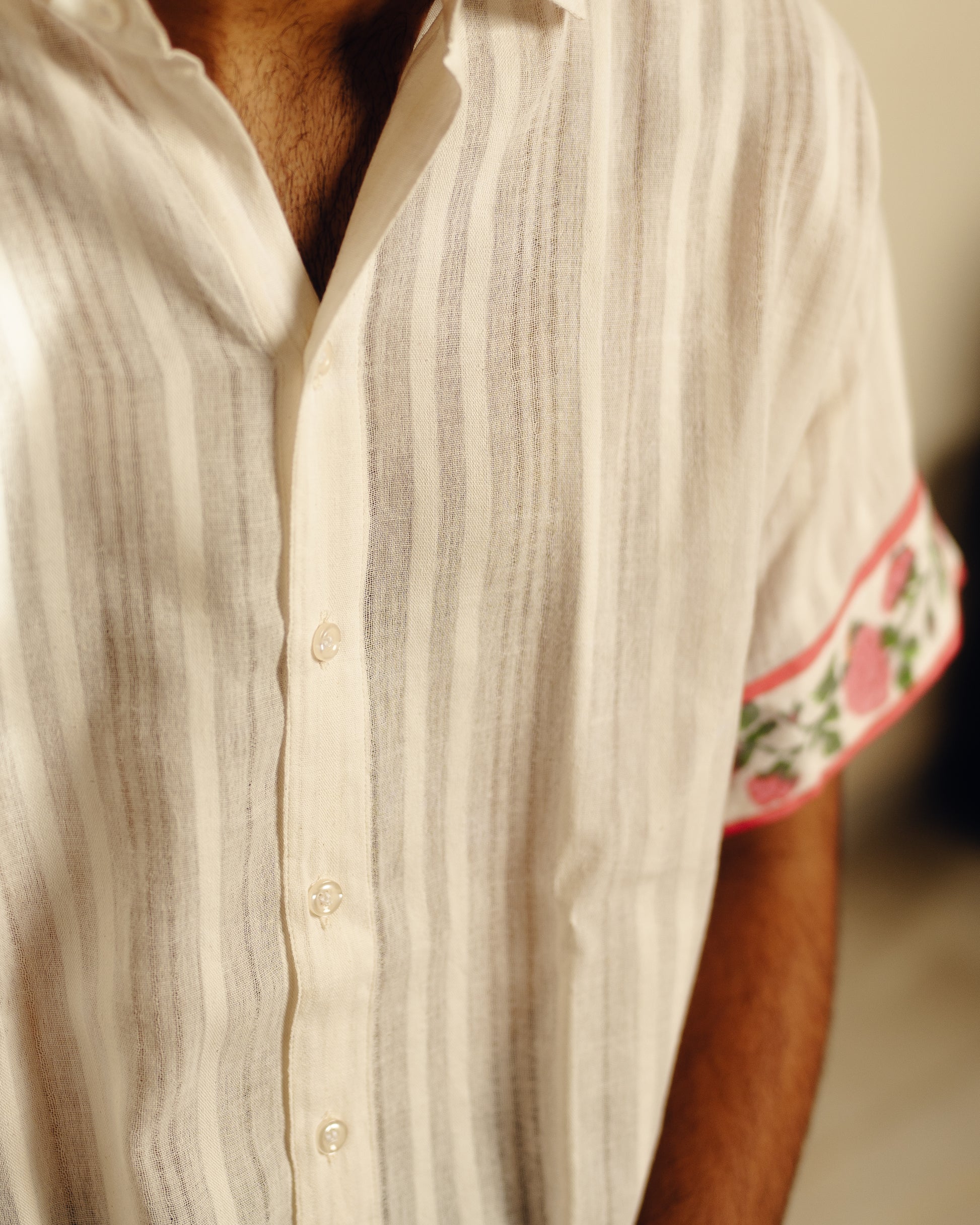 Close-up of a person wearing a white striped shirt with floral cuffs.