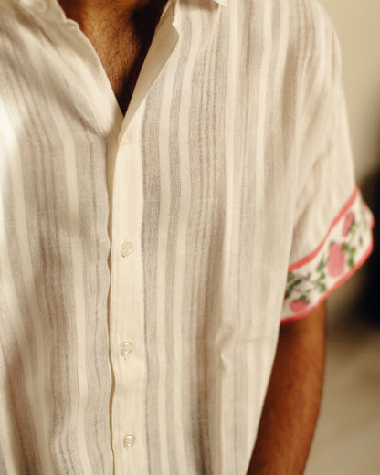 Close-up of a person wearing a white striped shirt with floral cuffs.