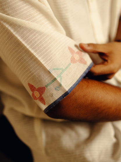 Close-up of a person wearing a white garment with floral embroidery on a dark background