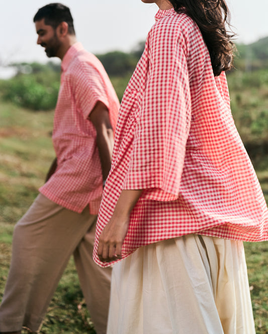 Two people wearing red and white checkered shirts in a field.