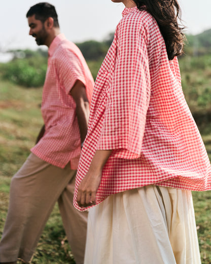 Two people wearing red and white checkered shirts in a field.