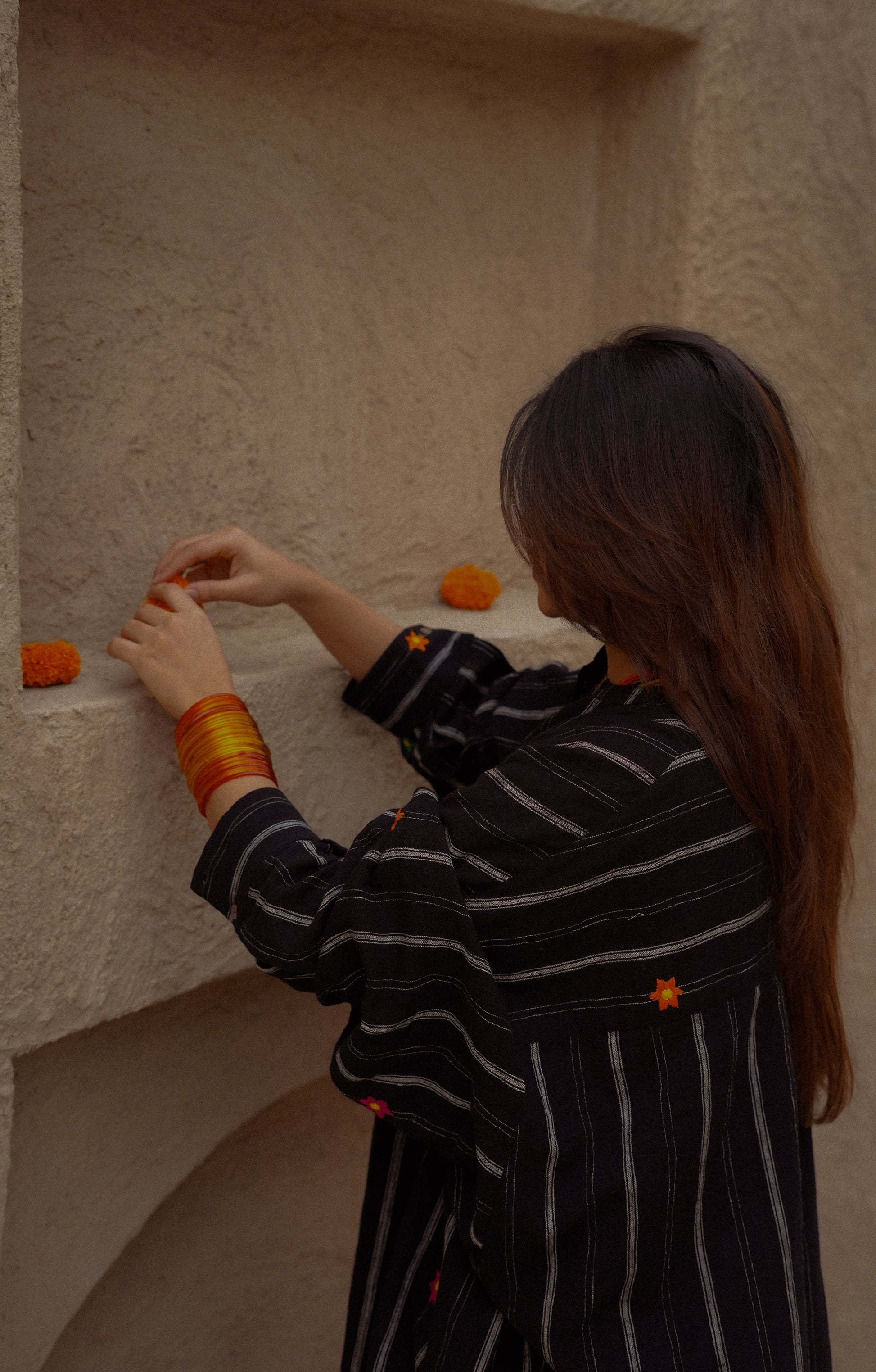Woman in a black and white striped outfit interacting with a textured wall.