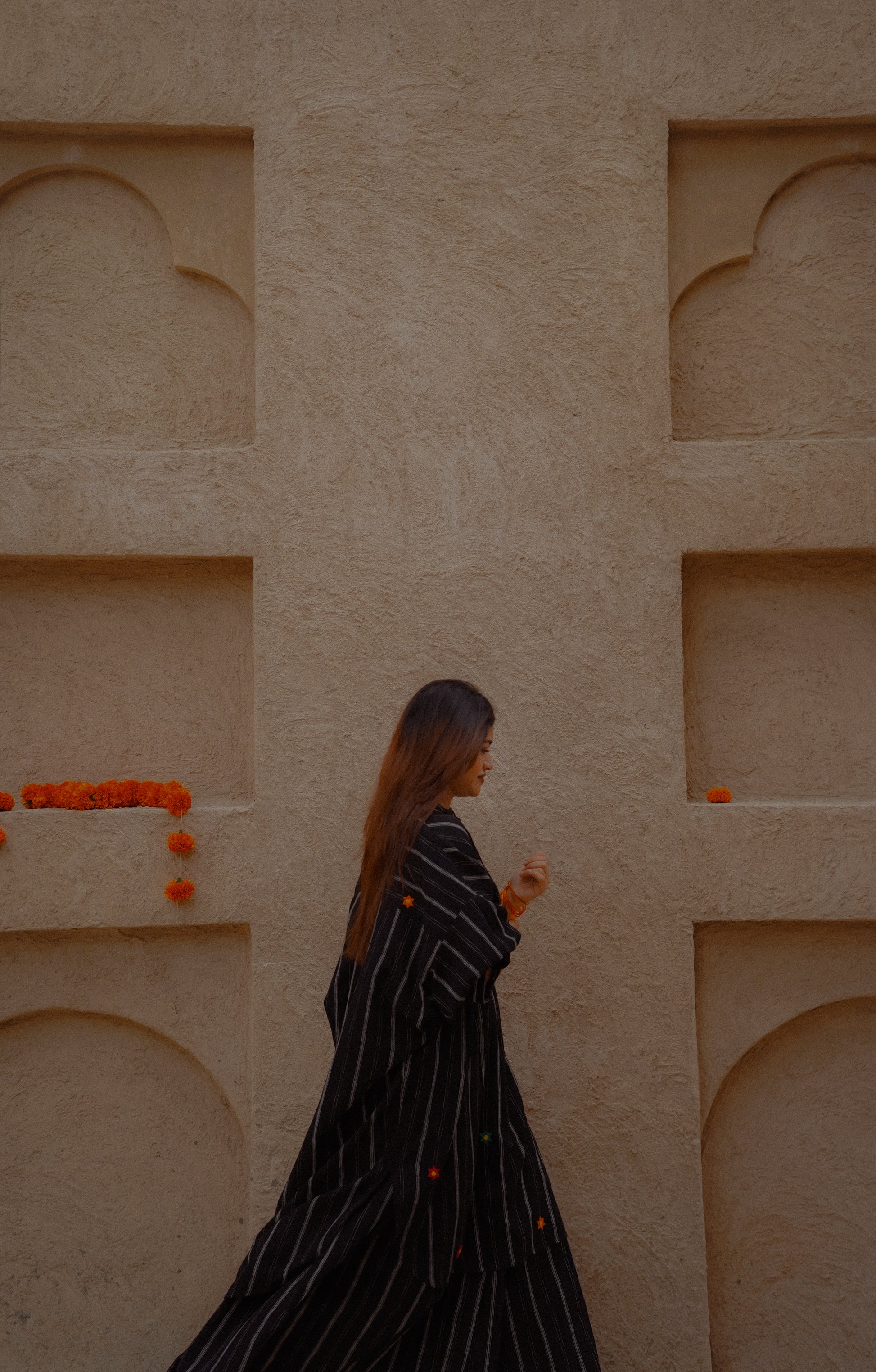 Woman walking past a beige wall with architectural details