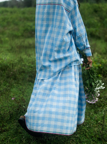 Person wearing a blue checkered outfit standing in a grassy field