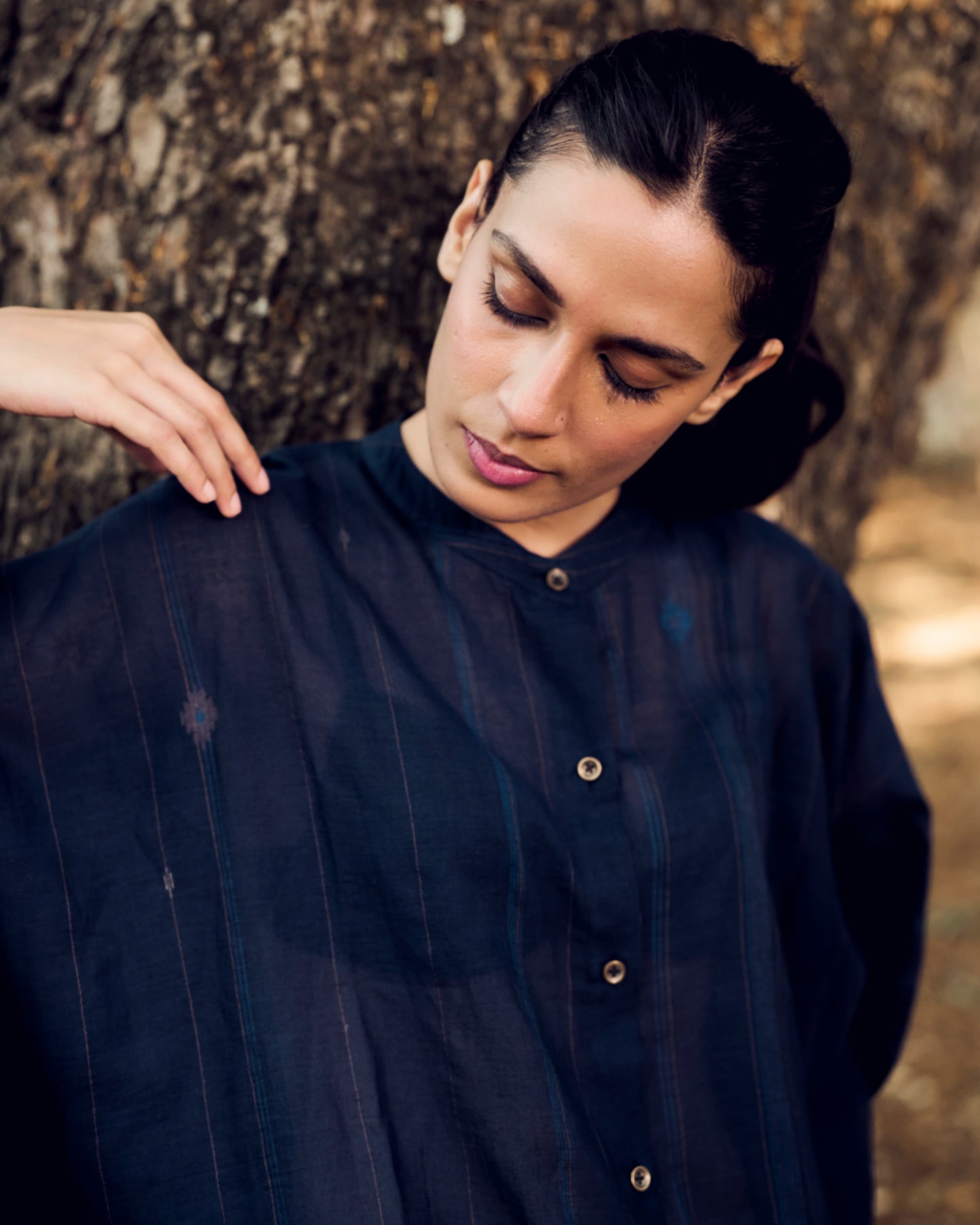 Person wearing a dark blue shirt against a natural background