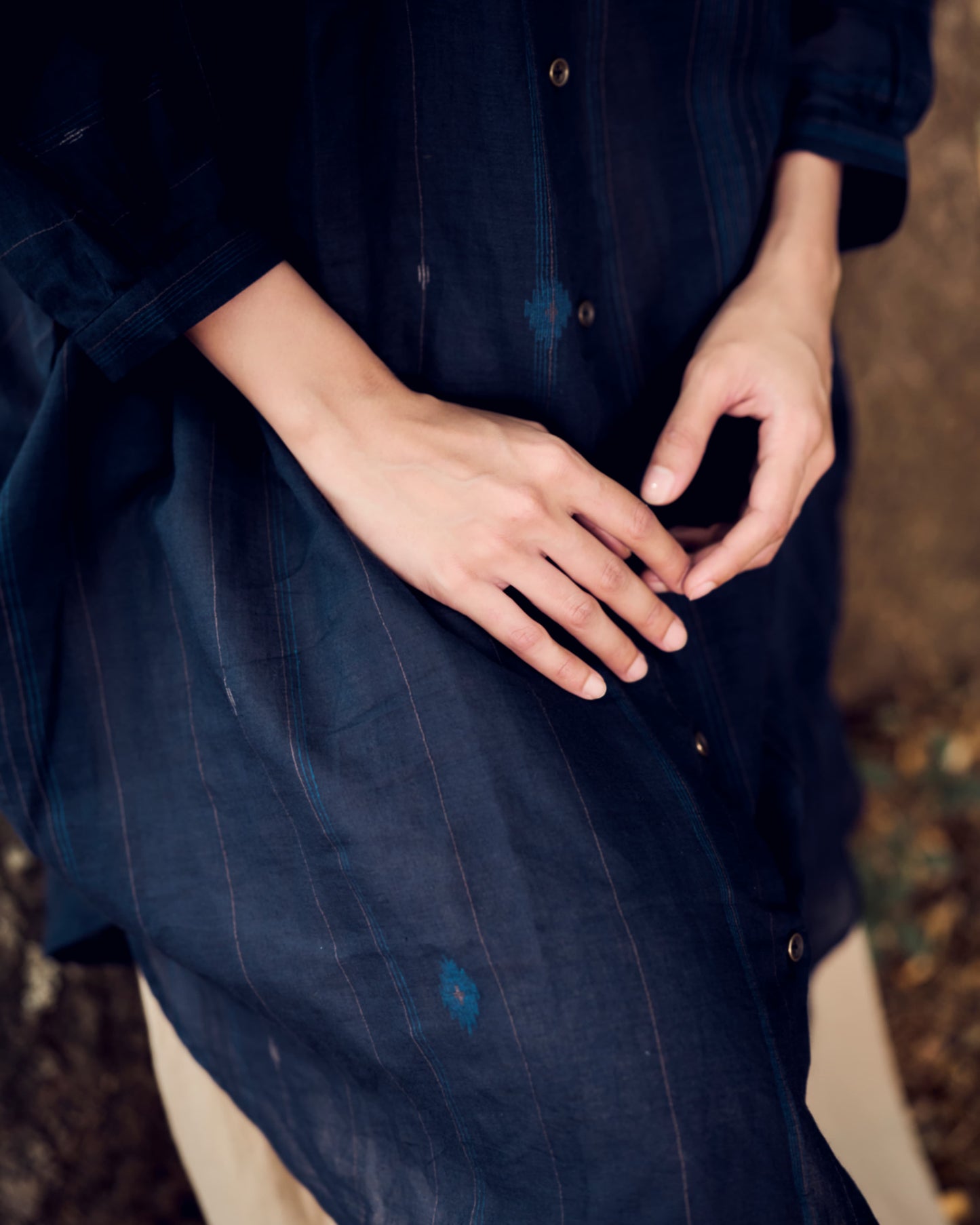Person wearing a dark blue shirt with hands clasped together