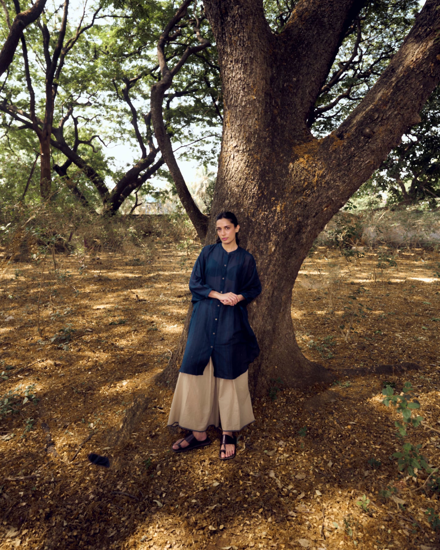 Woman standing under a large tree in a forested area
