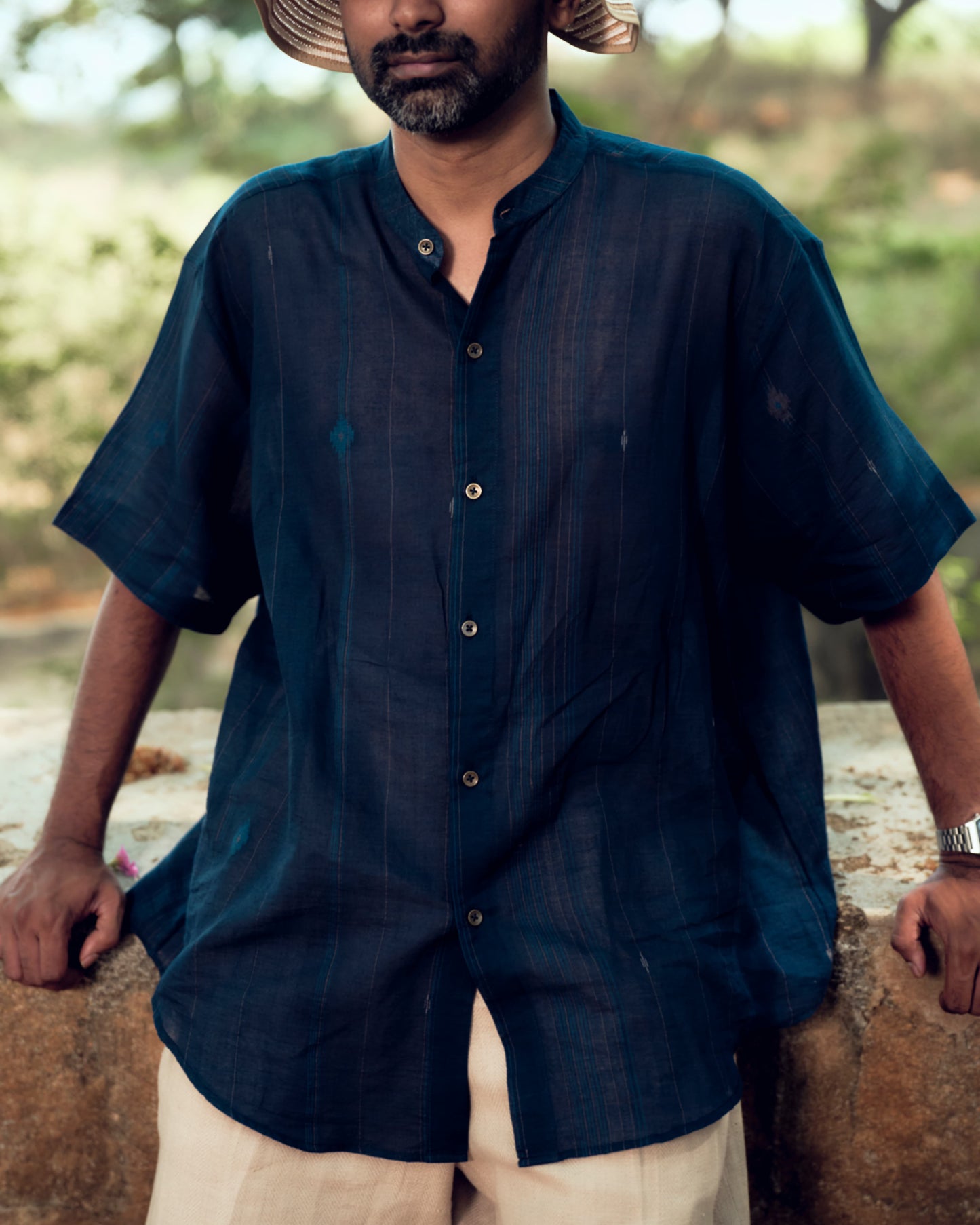 Man wearing a dark blue shirt outdoors with a blurred natural background