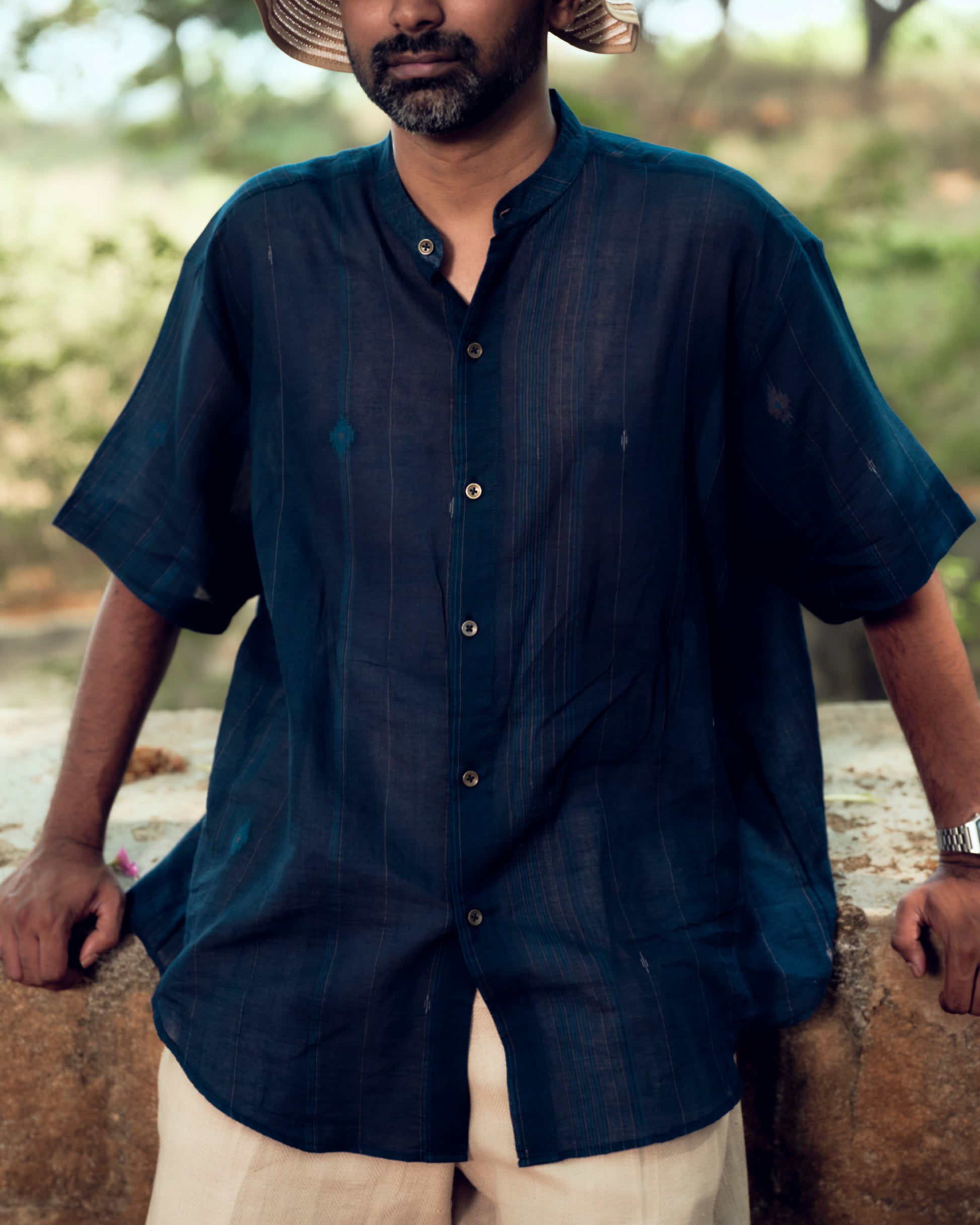 Man wearing a dark blue shirt outdoors with a blurred natural background