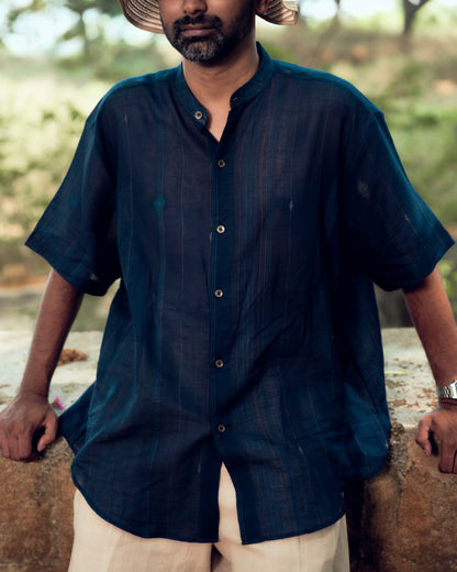 Man wearing a dark blue shirt outdoors with a blurred natural background