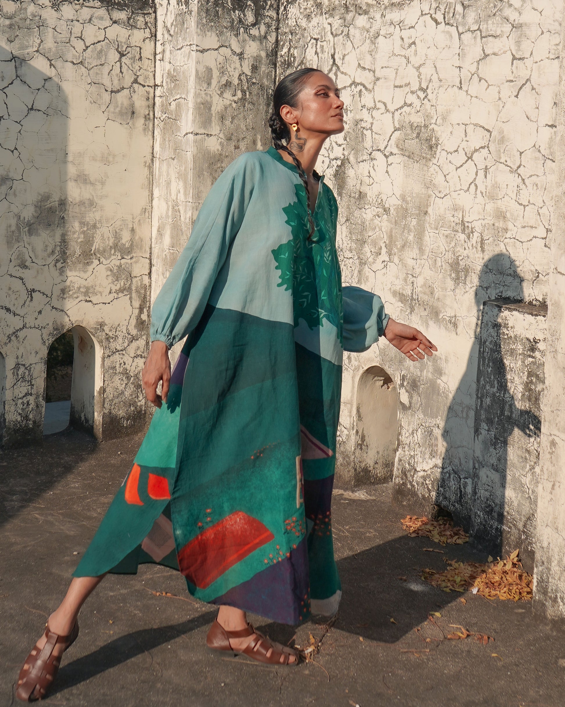 Woman wearing an olive green patterned dress in an outdoor setting