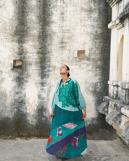 Woman in a colorful dress standing against a textured wall.