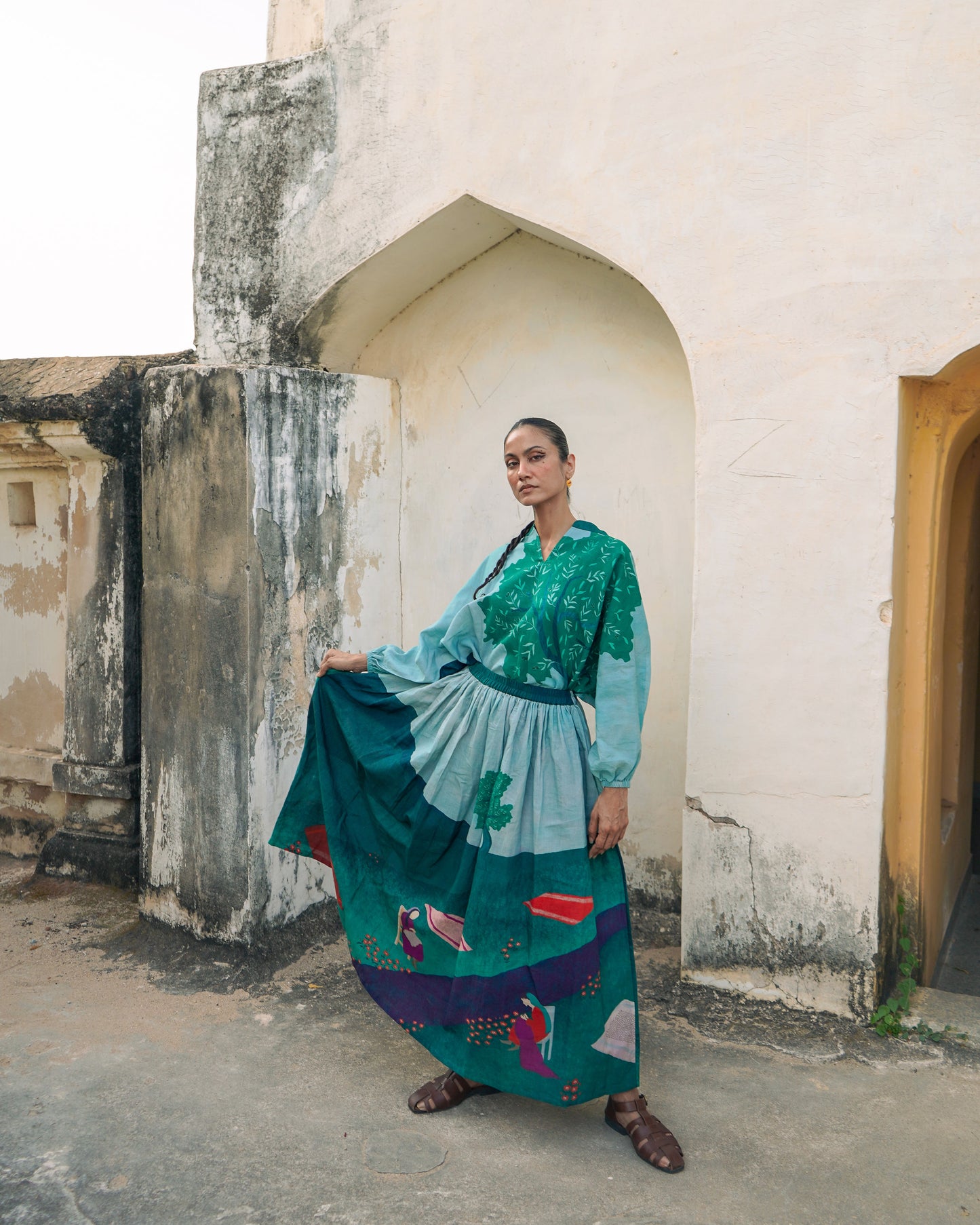 Woman in a colorful dress standing in front of an arched doorway.