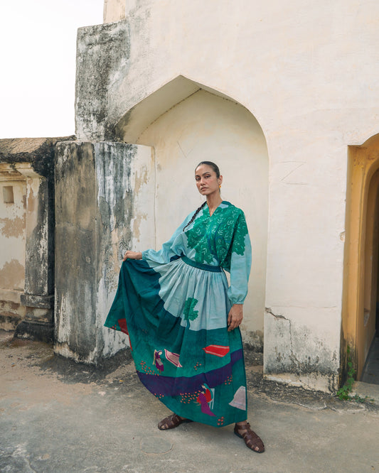 Woman in a colorful dress standing in front of an arched doorway.