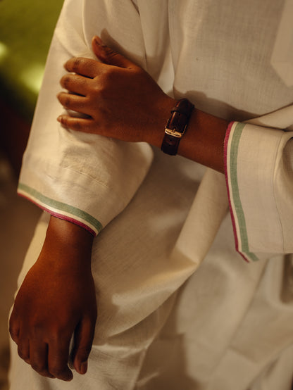Close-up of a person wearing a Oversized kurta - White with green trim, holding their arm.