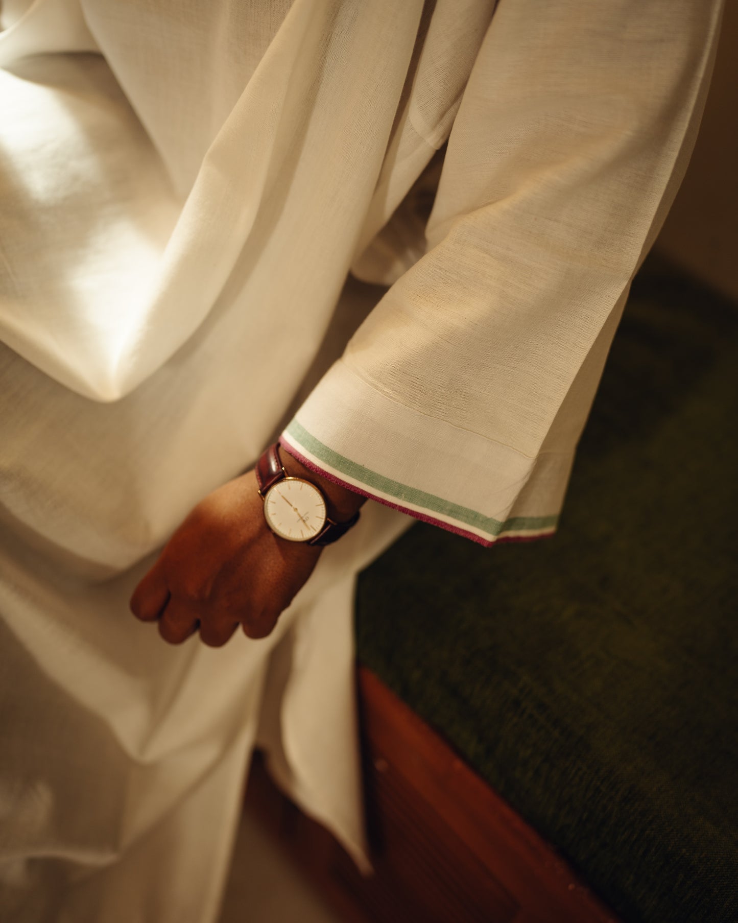 Person wearing a white traditional outfit with a watch on a blurred background