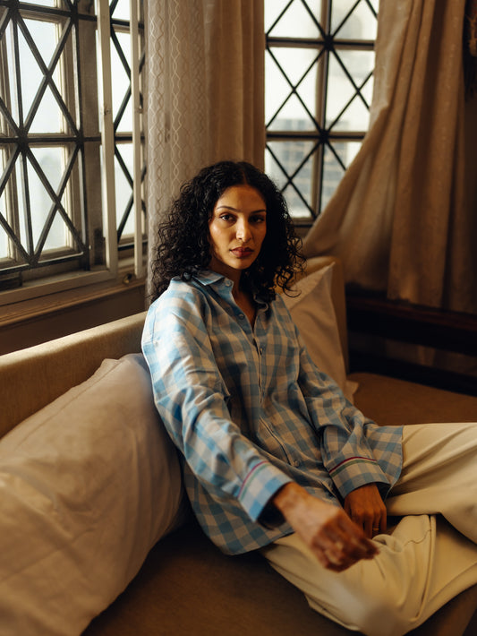 Woman in Oversized shirt - Light blue checks sitting on a couch by a window
