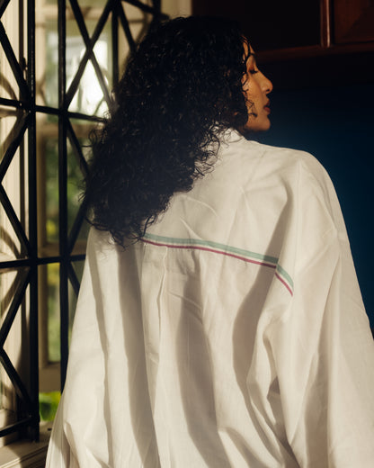 Person wearing a Oversized shirt - White with colorful stripes in a sunlit room