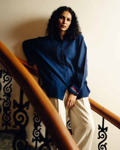 Woman in a blue shirt and white pants standing on a staircase.