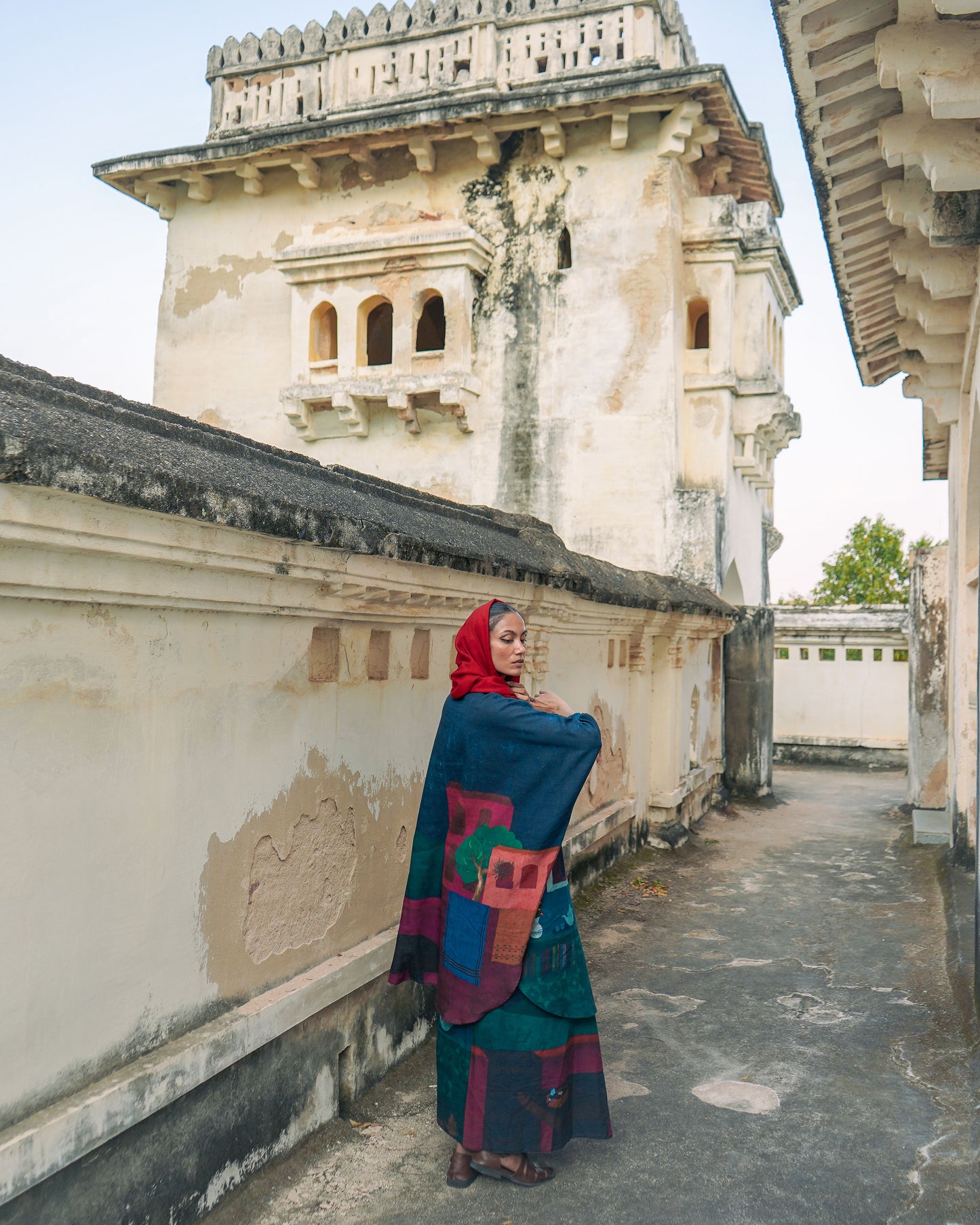 Woman in a colorful dress standing in front of an old architectural building.