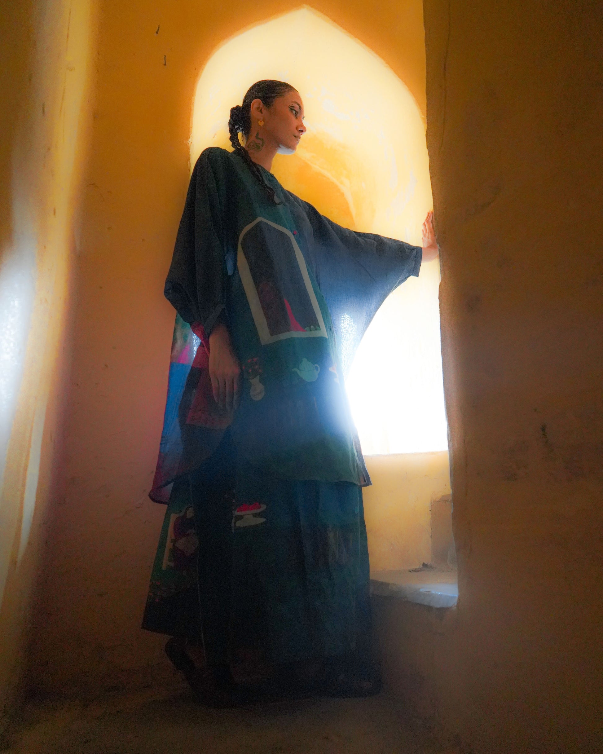 Woman in a colorful dress standing in a doorway with warm lighting