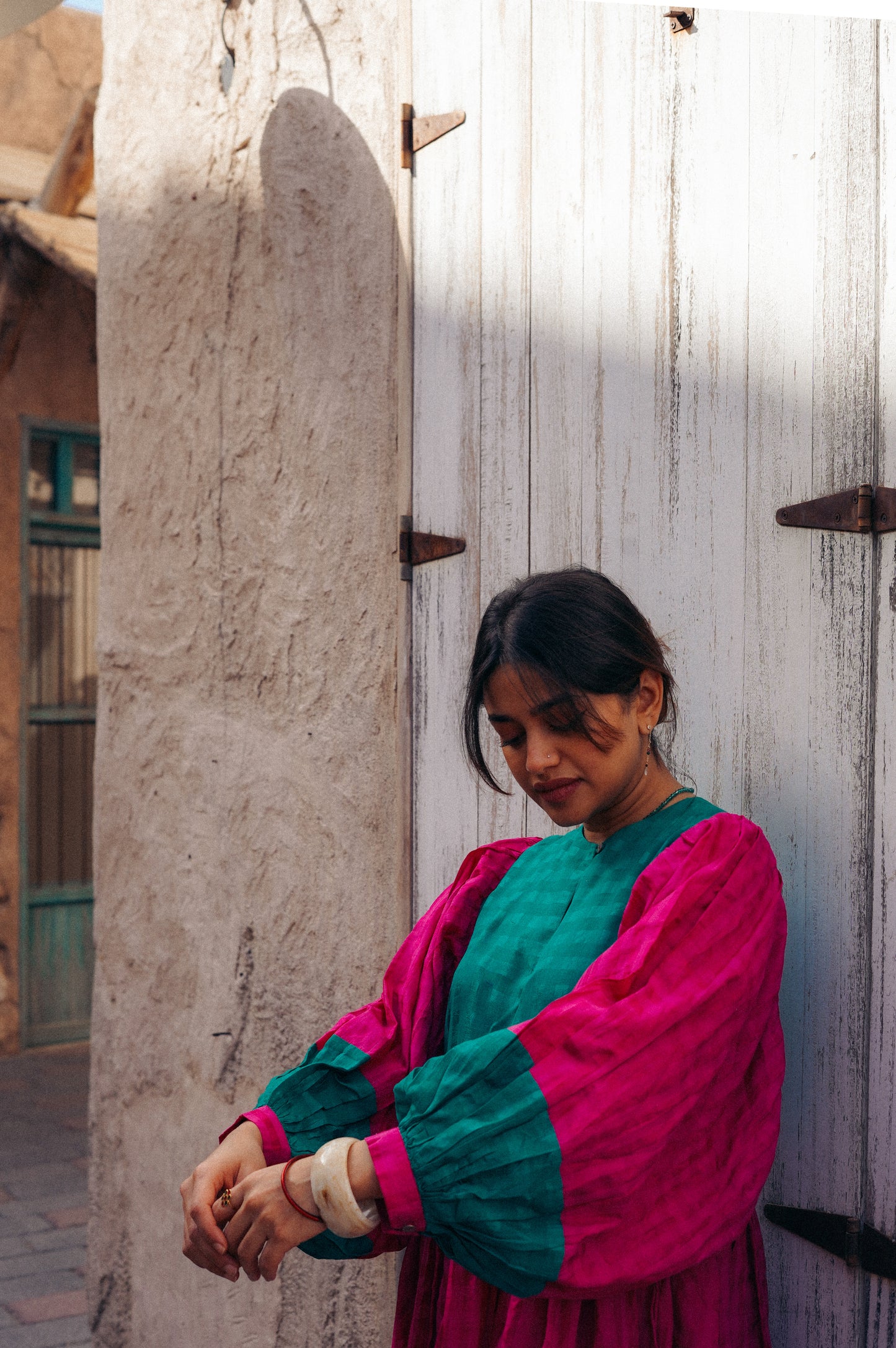 Woman in a colorful outfit standing next to a wooden door.