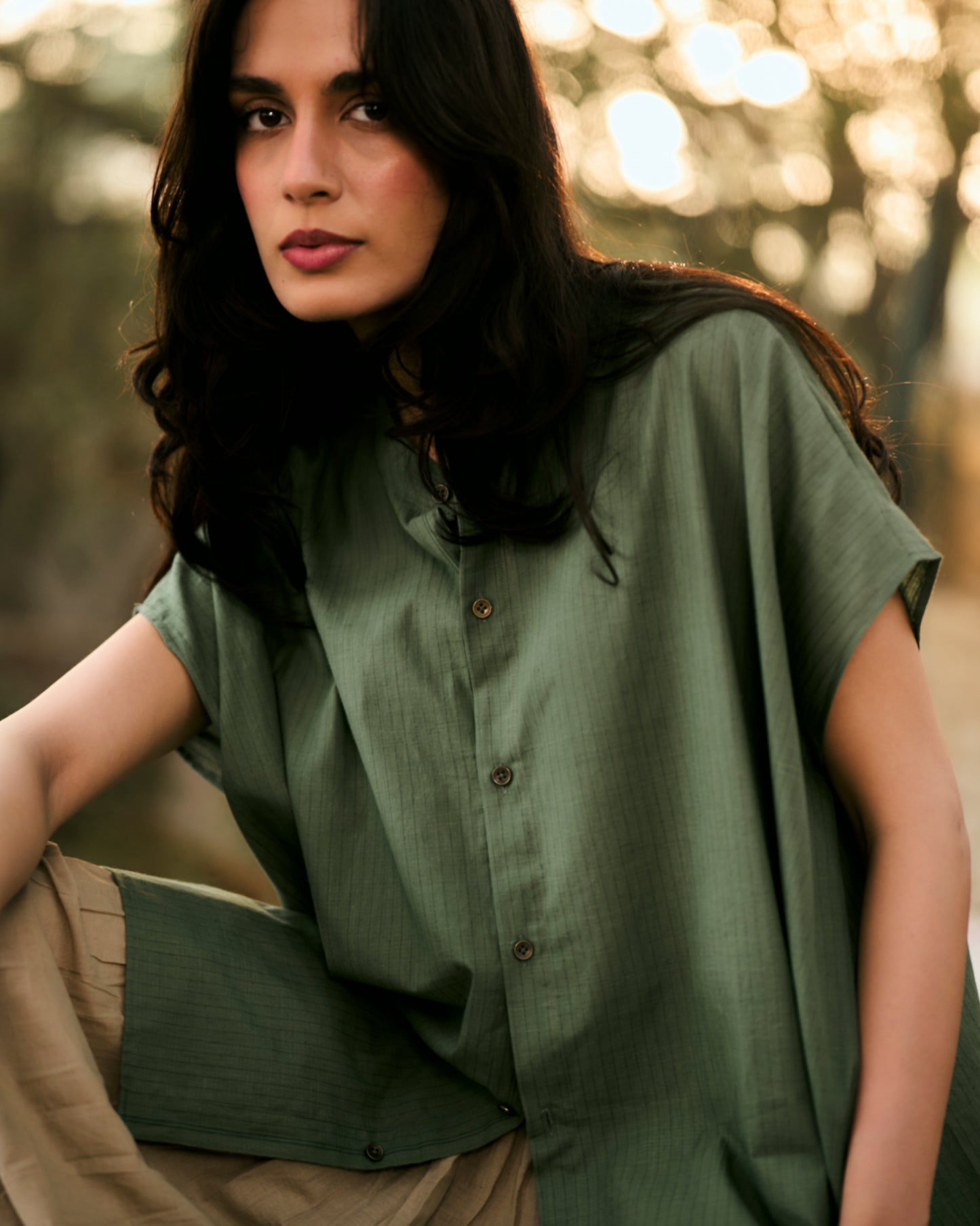 Woman wearing a green shirt with a blurred natural background