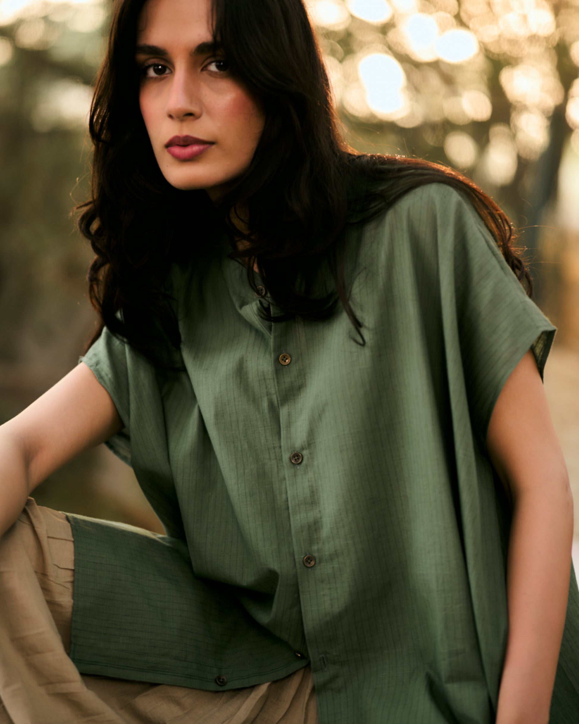 Woman wearing a green shirt with a blurred natural background