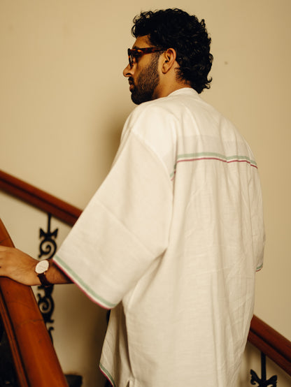 Man in a white traditional outfit White relaxed shirt standing on a staircase