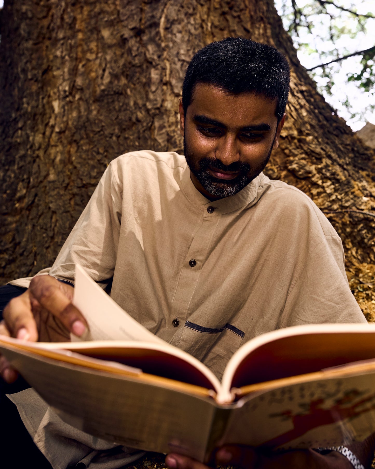 Man reading a book under a tree