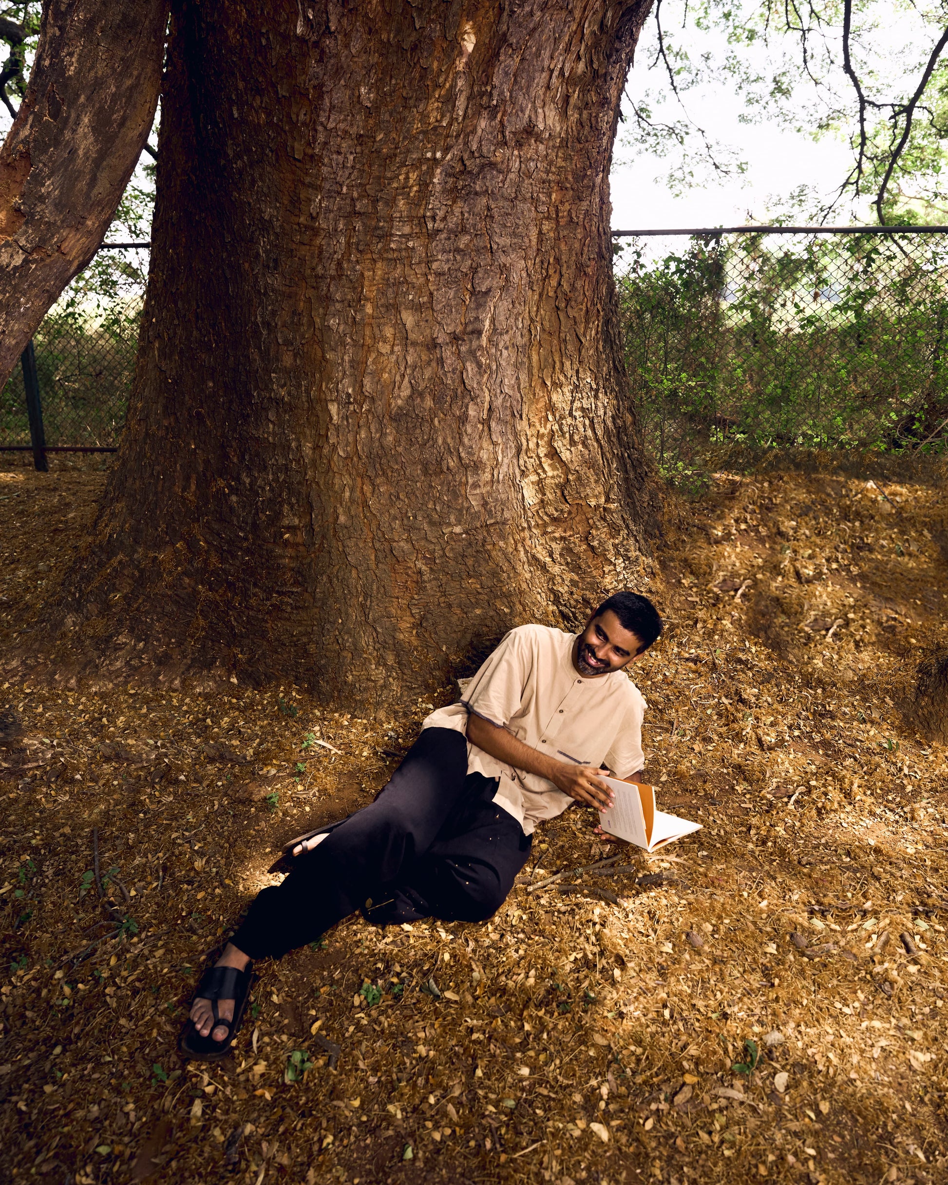 Man sitting under a large tree in a natural setting